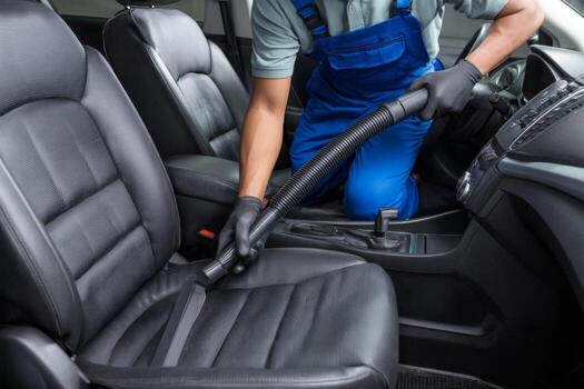 a man in blue overalls cleaning the interior of a car free photo